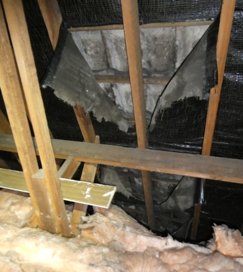 Perished roofing membrane hanging down into the roof space of an approximately 1960s semi-detached property.
