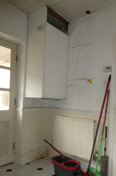 Extensive water damage to plastered and decorative finishes in a room below a bathroom, associated with the deteriorated condition of the bathroom above.
